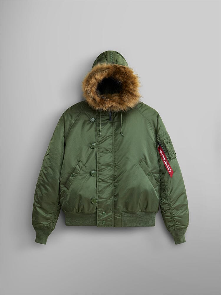 Alpha Industries N-2B Short Waist Parka in Sage: short waist bomber jacket with water repellent finish, faux mouton fur-lined hood, ribbed cuffs and hem, flap pockets, and red Remove Before Flight tag on left sleeve.