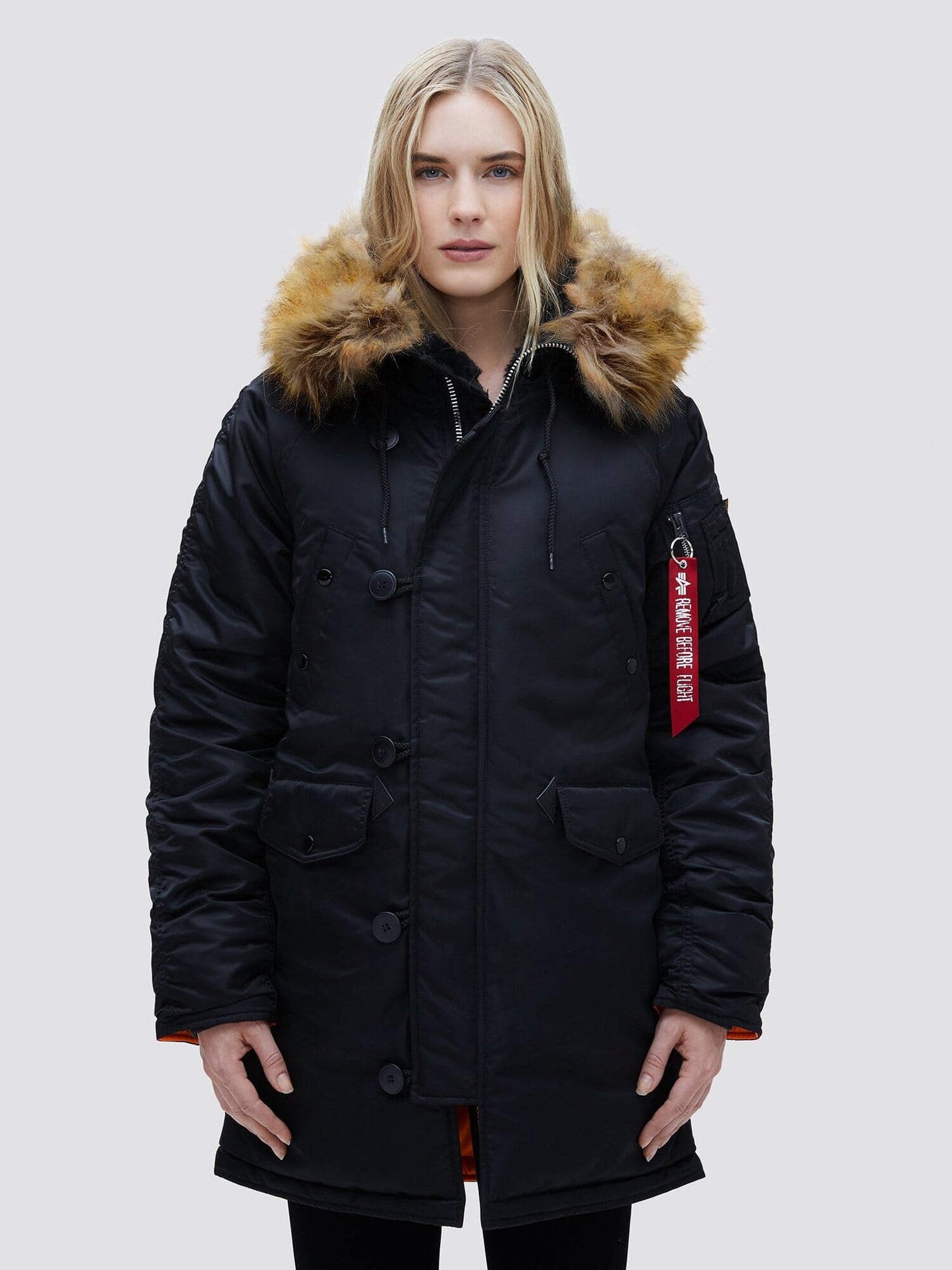 Alpha Industries N-3B Womens Parka in black with fur-lined snorkel hood, utility pocket, and red tag on left sleeve.
