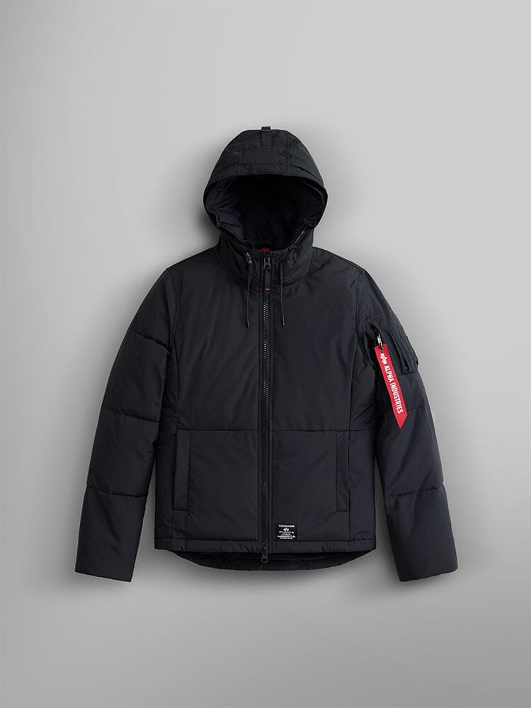 Alpha Industries Short Parka W, black hooded puffer jacket with front zipper, utility pockets, and red Remove Before Flight tag on left sleeve.
