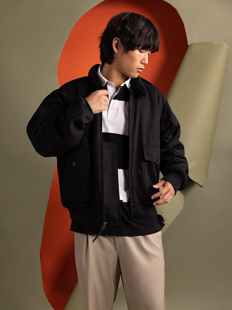 A person wearing an Alpha Industries 1940s B-10 Bomber Jacket over a striped shirt.