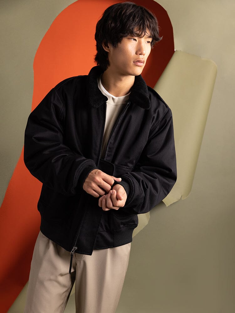 A person wearing a 1940s B-10 Bomber Jacket by Alpha Industries stands over a white shirt.
