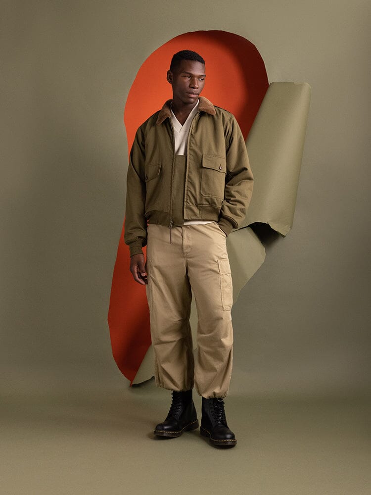 A person wearing a 1940s B-10 Bomber Jacket in olive, by Alpha Industries.