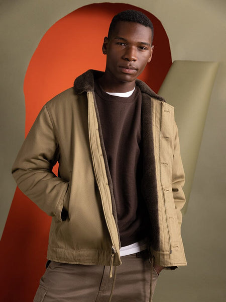 An individual dressed in an Alpha Industries 1940s N-1 Deck Jacket in khaki, featuring a cotton shell.