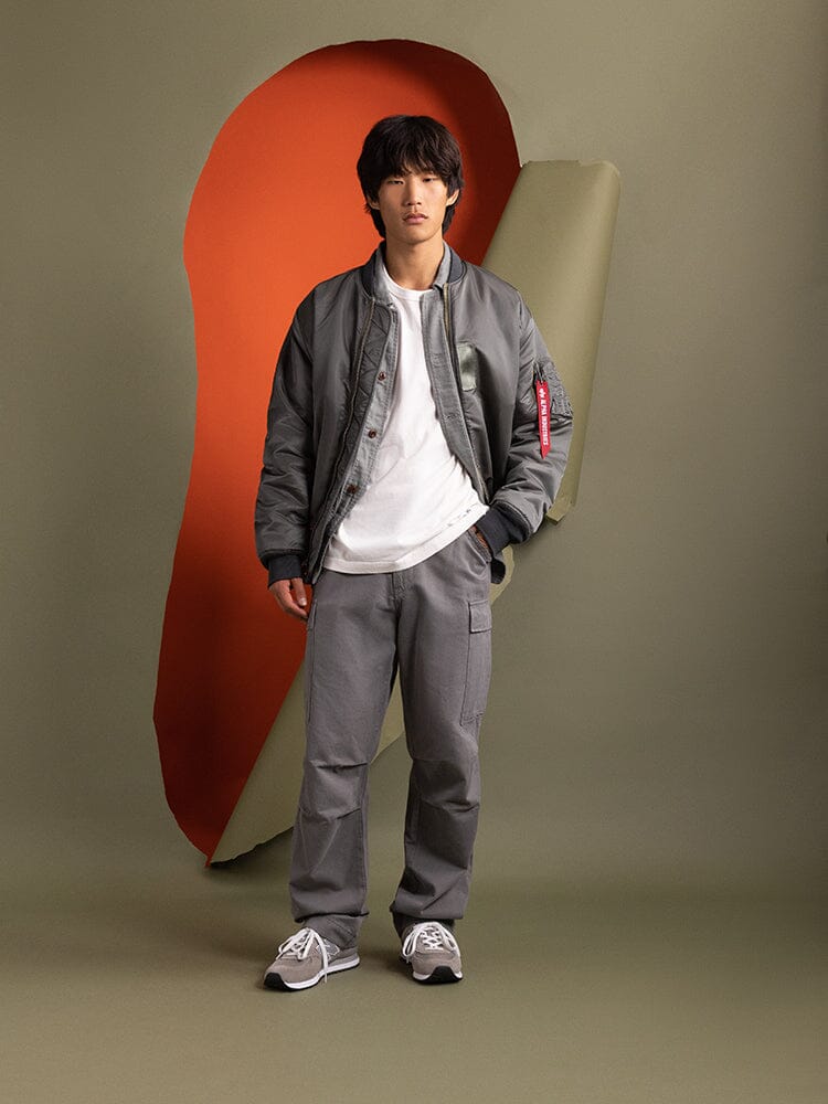 A man wearing a gray 1960s MA-1 Bomber Jacket by Alpha Industries.