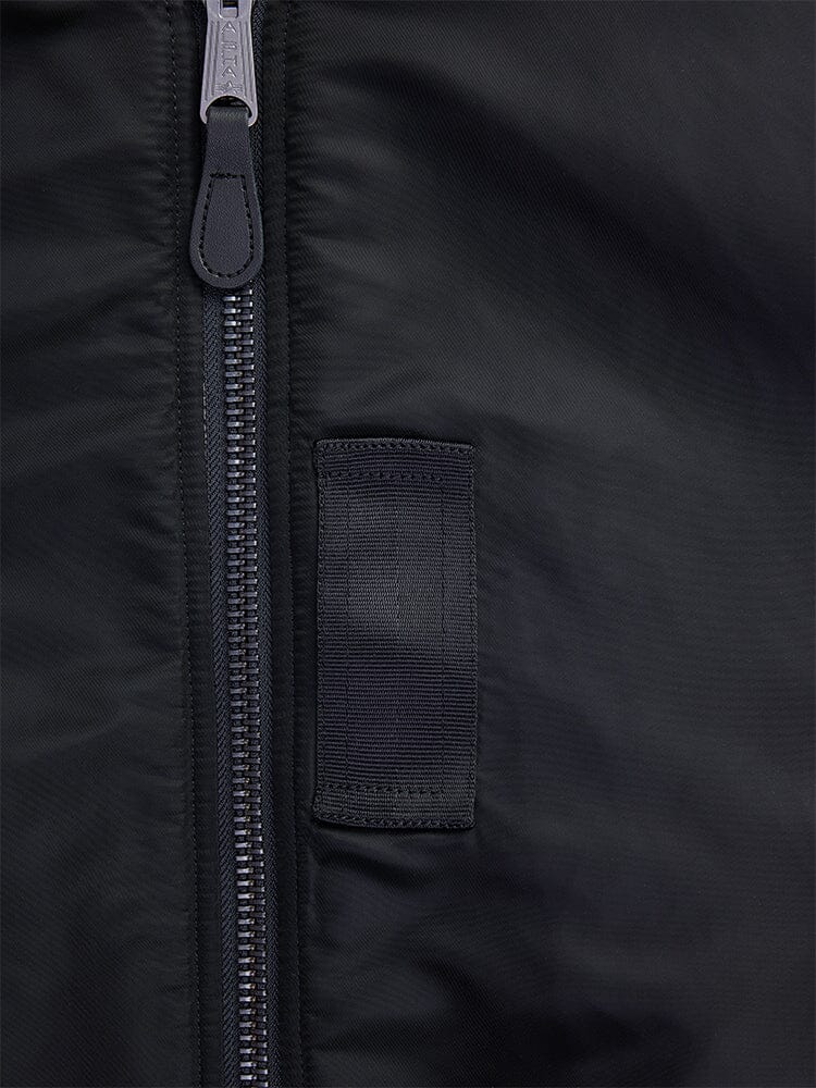 Close-up of the 1960s MA-1 Bomber Jacket in black by Alpha Industries, featuring a silver zipper and a small black fabric loop.