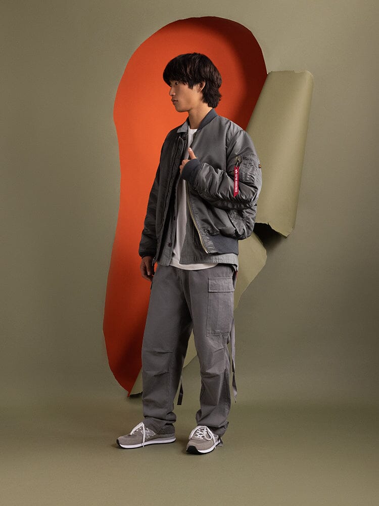 A person wearing a Gray 1960s MA-1 Bomber Jacket by Alpha Industries.