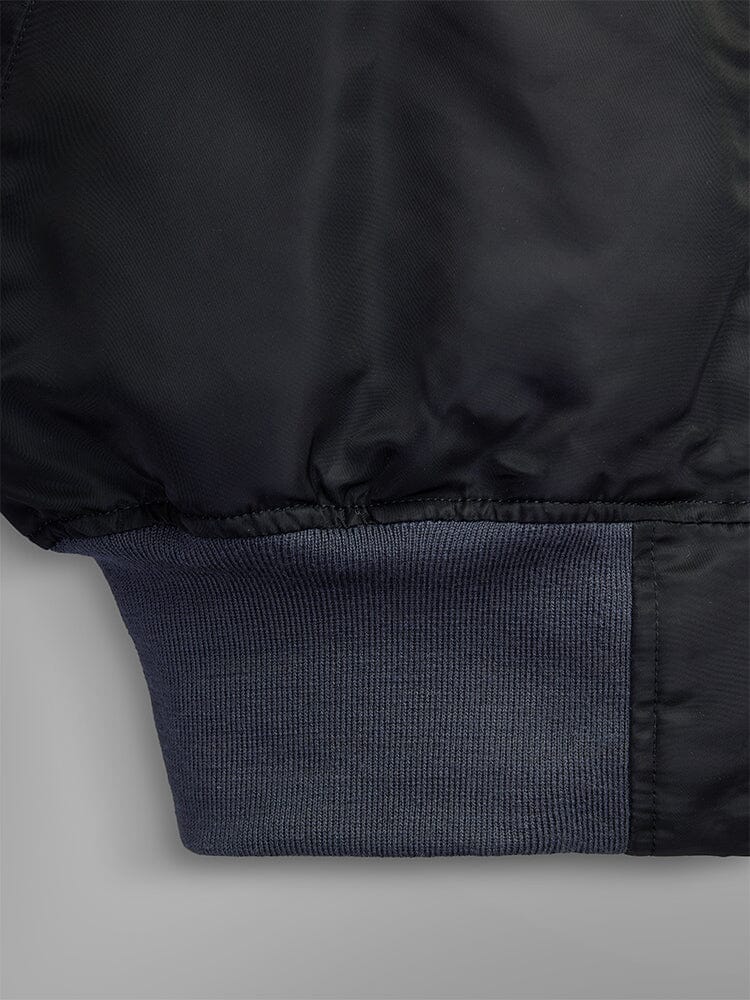 Close-up of a sleeve from the 1960s MA-1 Bomber Jacket in black by Alpha Industries, featuring a gray ribbed cuff.