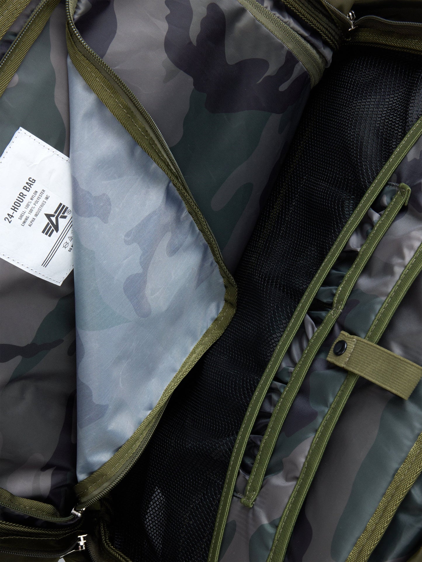 Alpha Industries 24 Hr Bag, camouflage pattern, mesh and fabric compartments, green zippers, white 24 HR BAG label, nylon construction.