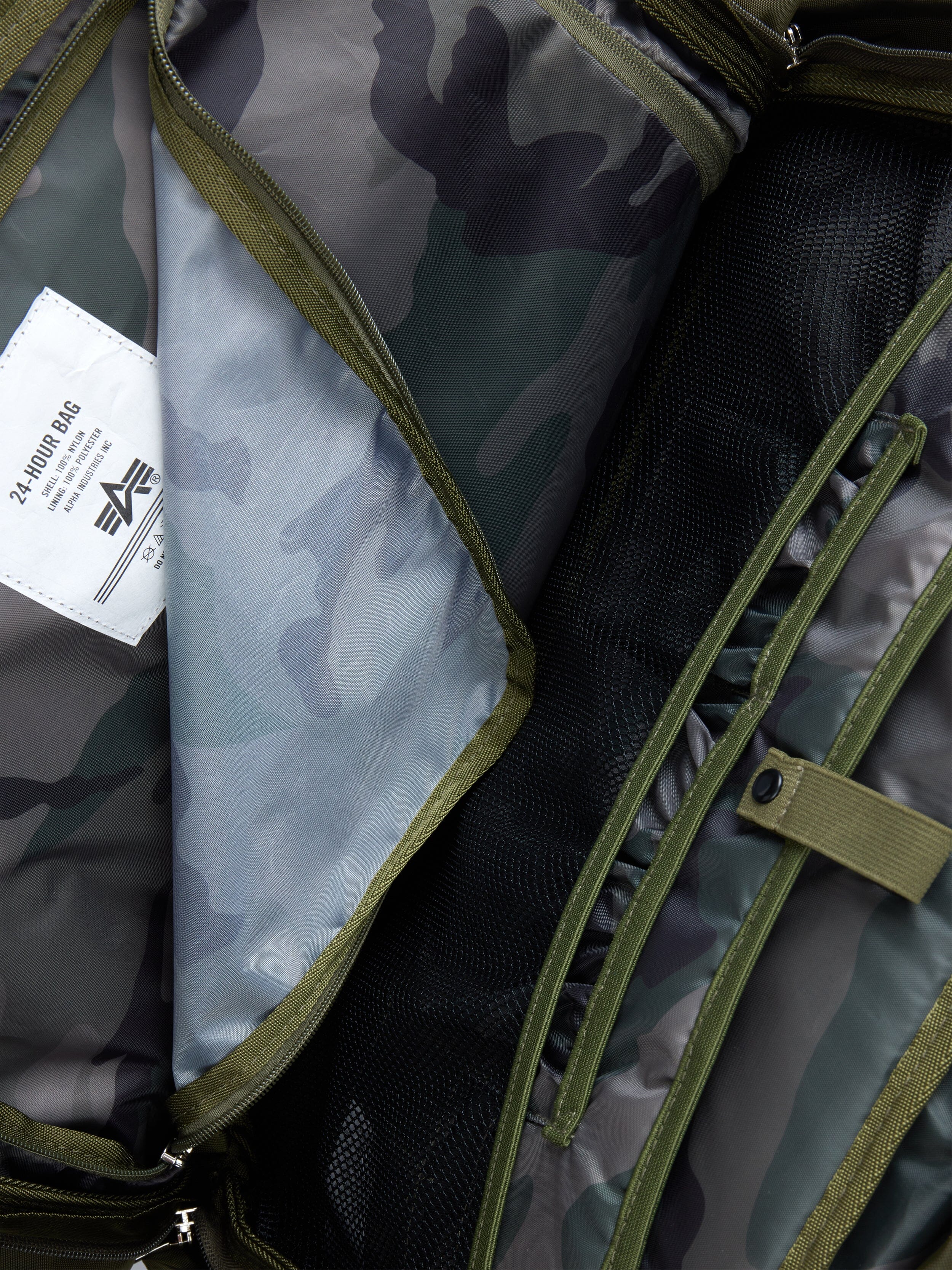 Alpha Industries 24 Hr Bag, camouflage pattern, mesh and fabric compartments, green zippers, white 24 HR BAG label, nylon construction.