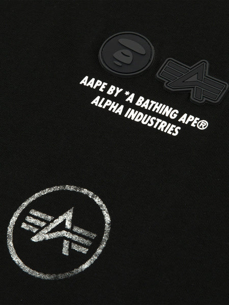 Close-up of the AAPE X Alpha Industries Somewhere In Universe Tee 
 featuring black fabric with graphic AAPE BY *A BATHING APE® ALPHA INDUSTRIES and logos.