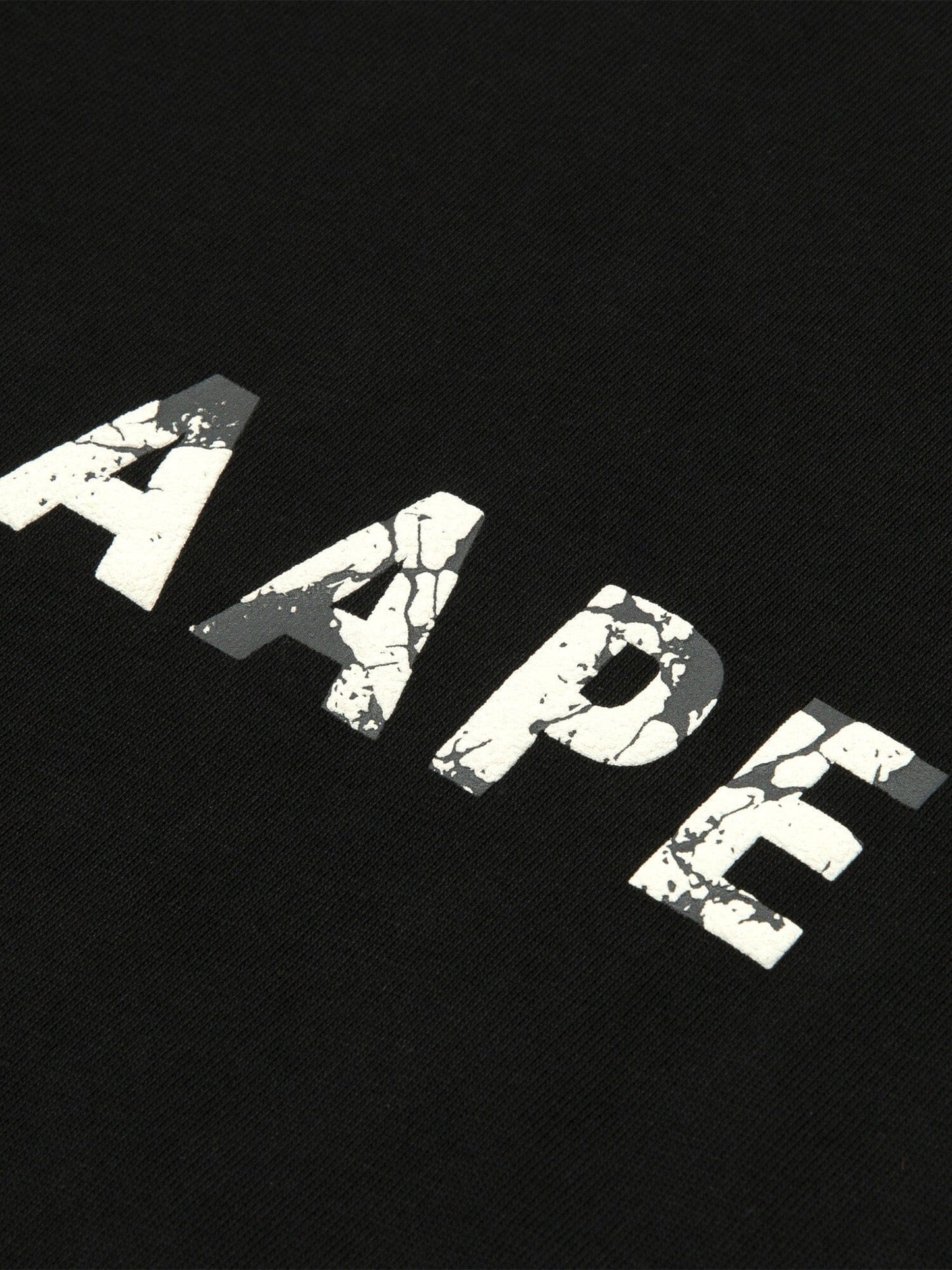 The AAPE x Alpha Somewhere In Universe Tee by Alpha Industries Features Vintage Distressed White AAPE Text on Black Fabric.