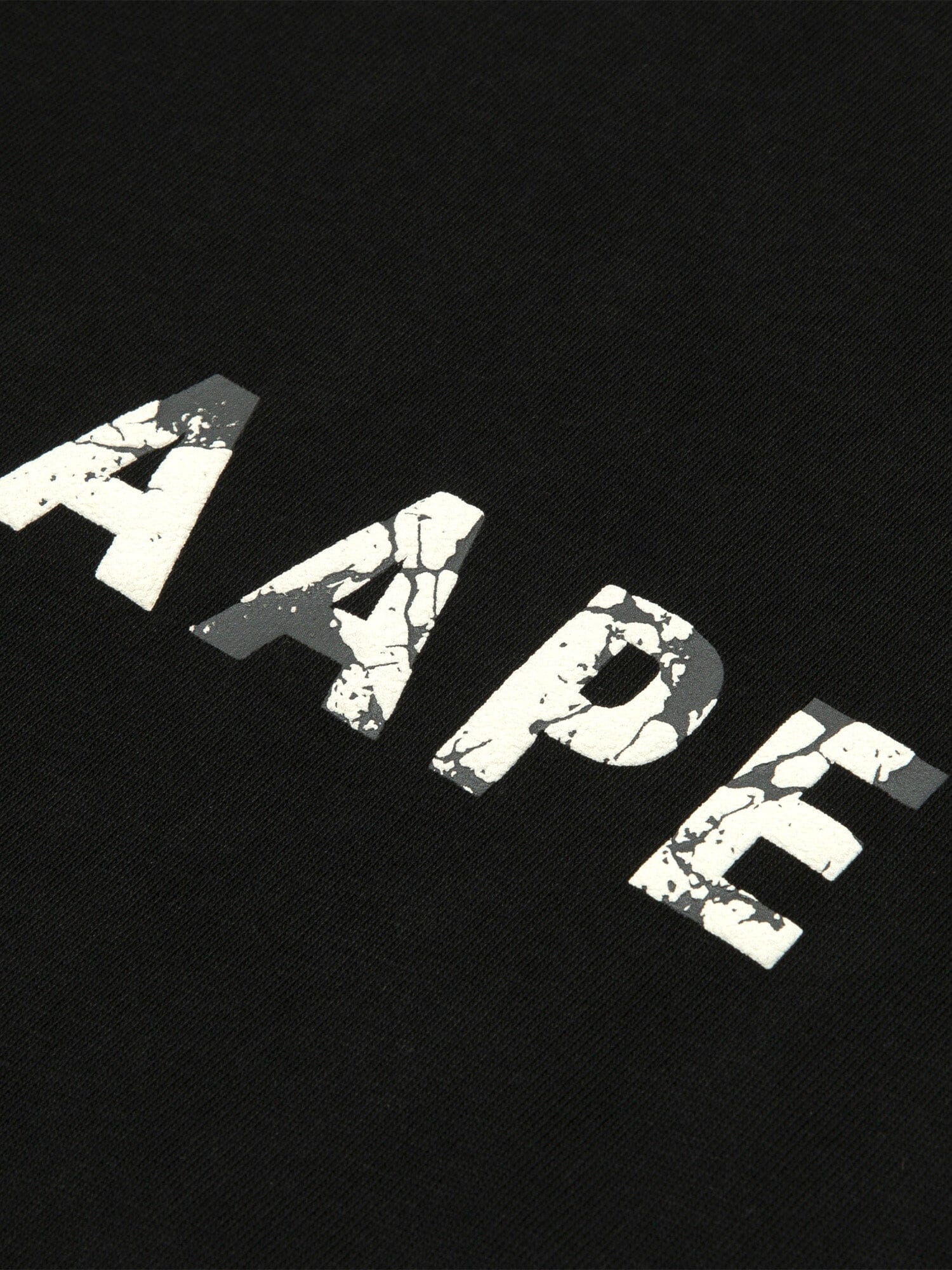The AAPE x Alpha Somewhere In Universe Tee by Alpha Industries Features Vintage Distressed White AAPE Text on Black Fabric.