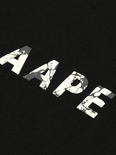 The AAPE x Alpha Somewhere In Universe Tee by Alpha Industries Features Vintage Distressed White AAPE Text on Black Fabric.