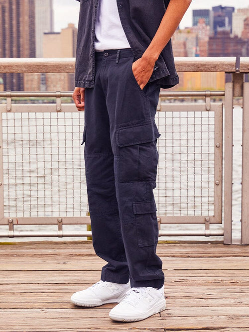 Alpha Industries Acu Pant cargo pants in navy, with side pockets, paired with white sneakers and a dark jacket.