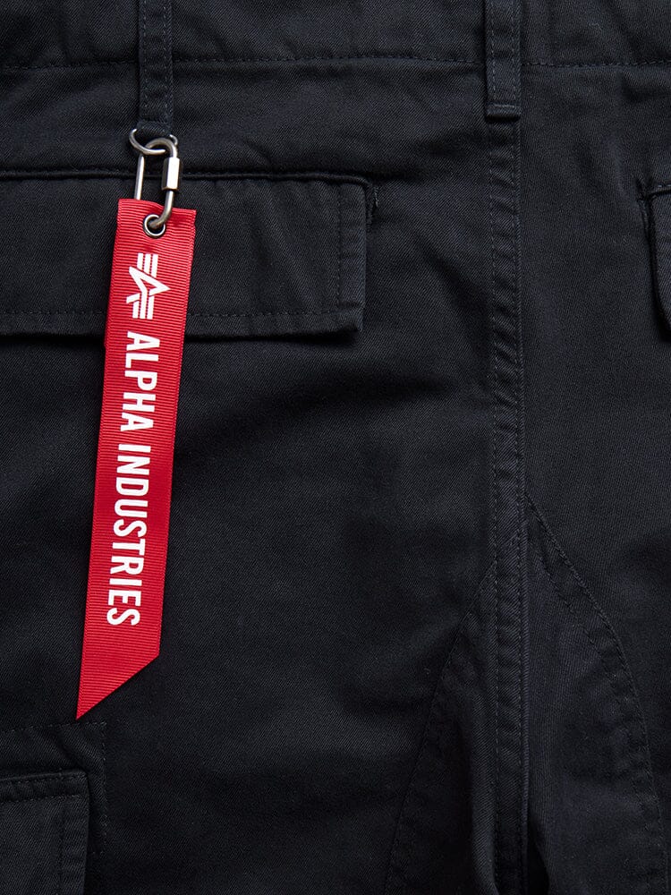 Acu Pant by Alpha Industries in black with utility pockets and a red Alpha Industries tag on a belt loop with a silver clip.