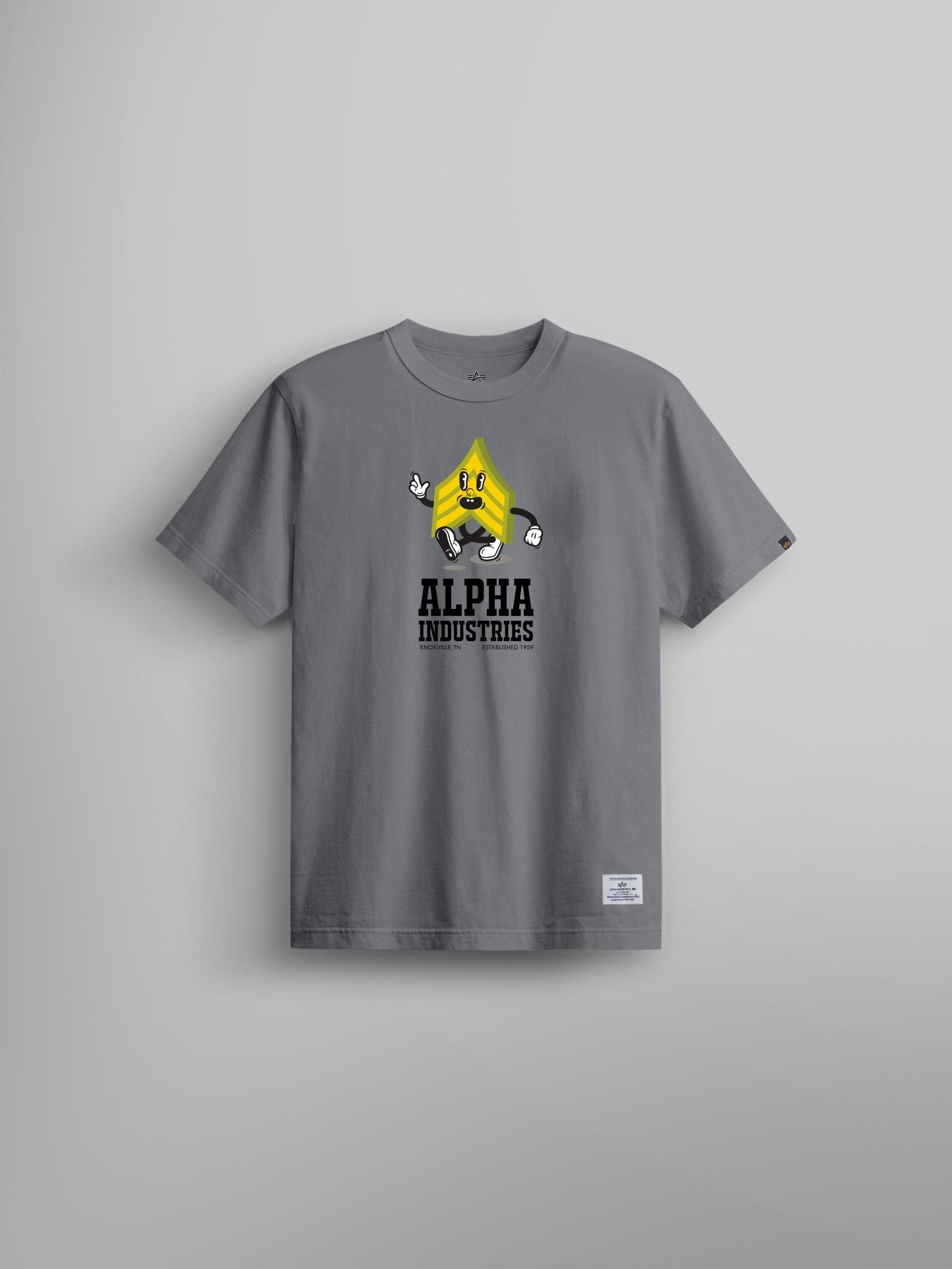 Alpha Badge Tee by Alpha Industries, aircraft gray t-shirt with yellow cartoon character graphic and Alpha Industries text on chest.