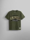 The Alpha Camo Logo Tee by Alpha Industries in olive green features a bold screen print with "Alpha Industries" and "Established 1959" in large letters on the front, incorporating an Alpha camo logo for a distinctive touch.
