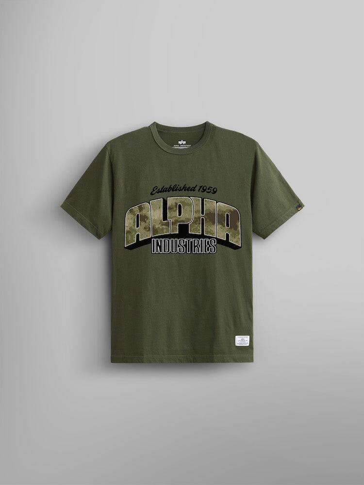 The Alpha Camo Logo Tee by Alpha Industries in olive green features a bold screen print with "Alpha Industries" and "Established 1959" in large letters on the front, incorporating an Alpha camo logo for a distinctive touch.