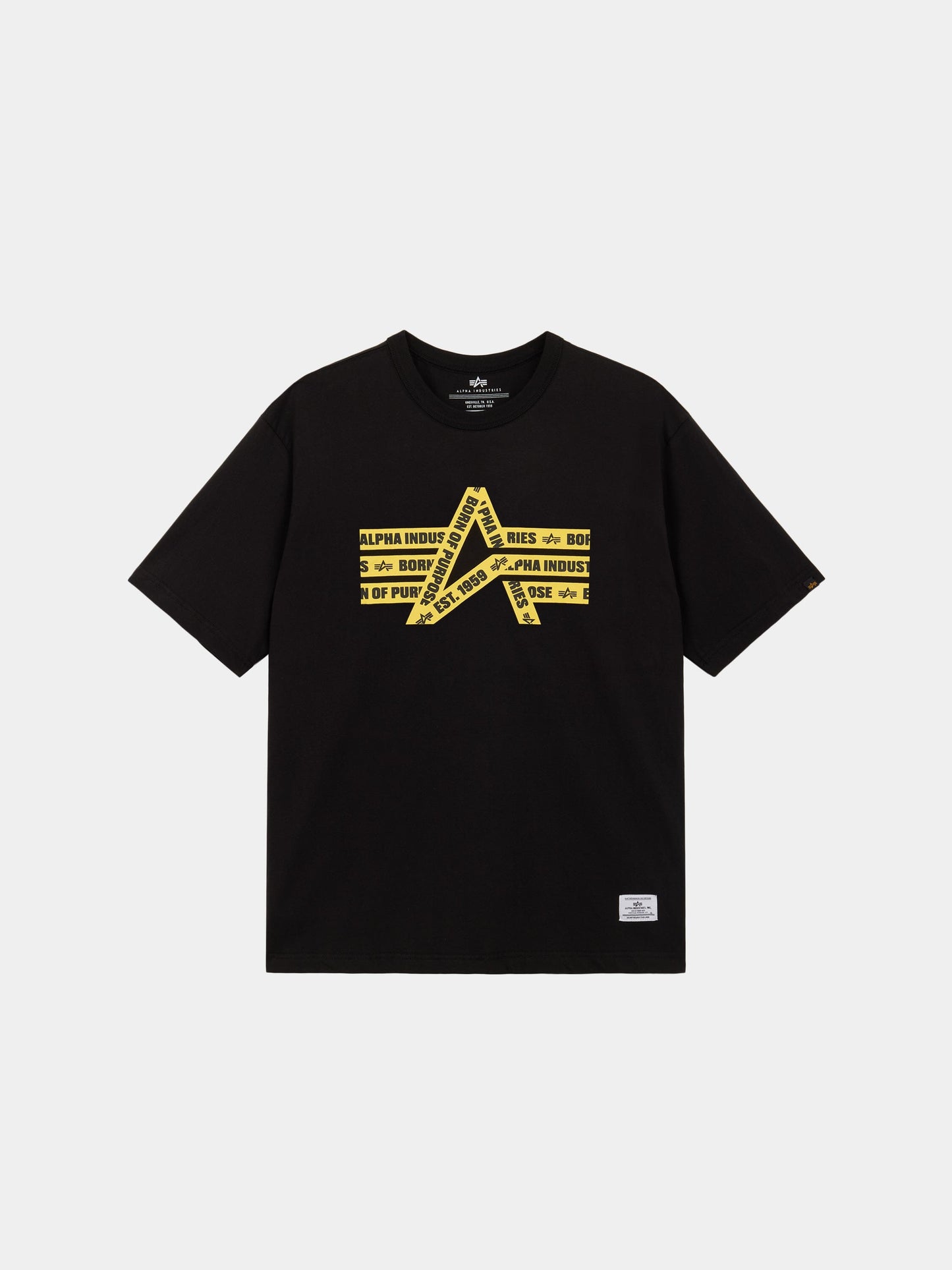 Alpha Caution Tape Tee by Alpha Industries is a black short-sleeve shirt with yellow graphic and diagonal Alpha Industries text on front.