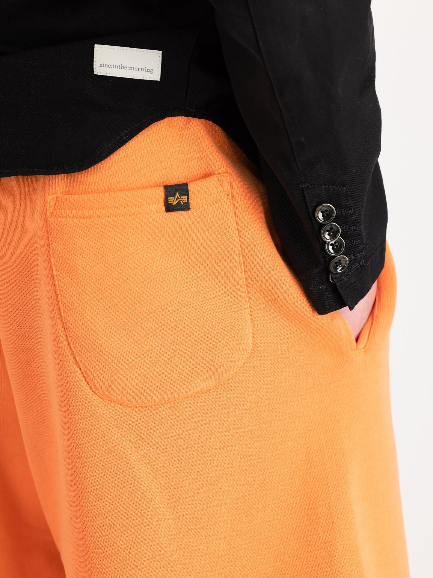 Alpha Essential Relaxed Short by Alpha Industries, orange cotton-blend shorts with back pocket. Black shirt with buttoned cuffs and almost the morning label.