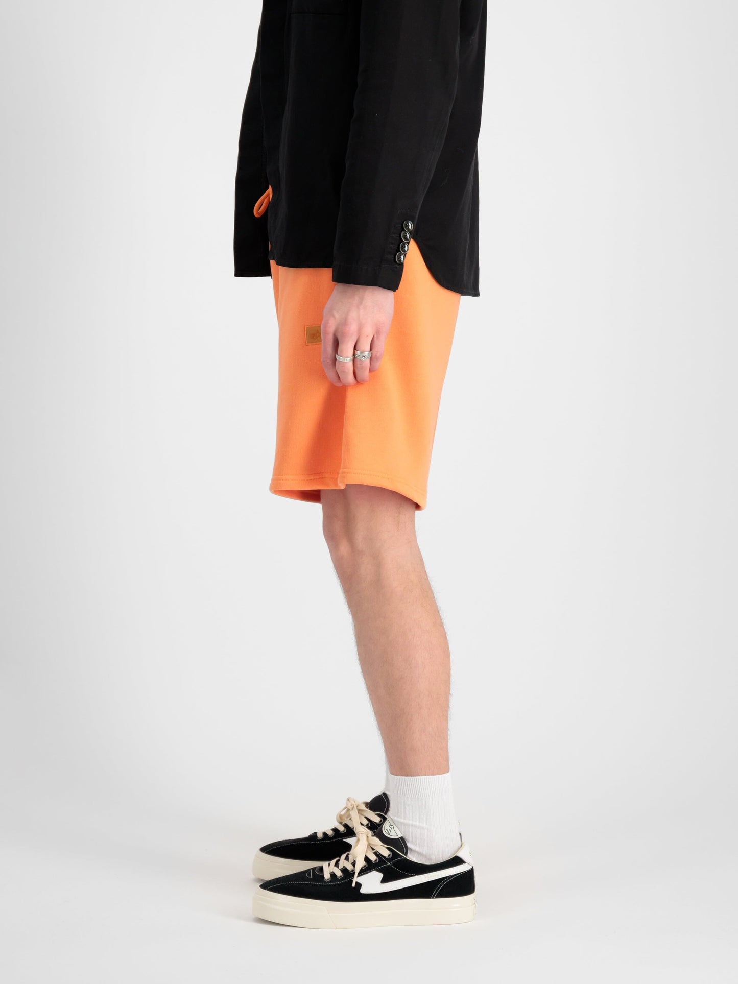 Alpha Industries Alpha Essential Relaxed Short in Orange, Black Cotton Blend Shirt, White Socks, Black-and-White Sneakers.