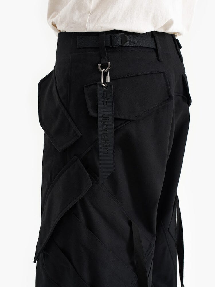 Curved Multi Pocket Trouser by Alpha Industries, black with experimental pattern, multiple pockets, curved silhouette, and black keychain strap on belt loop.