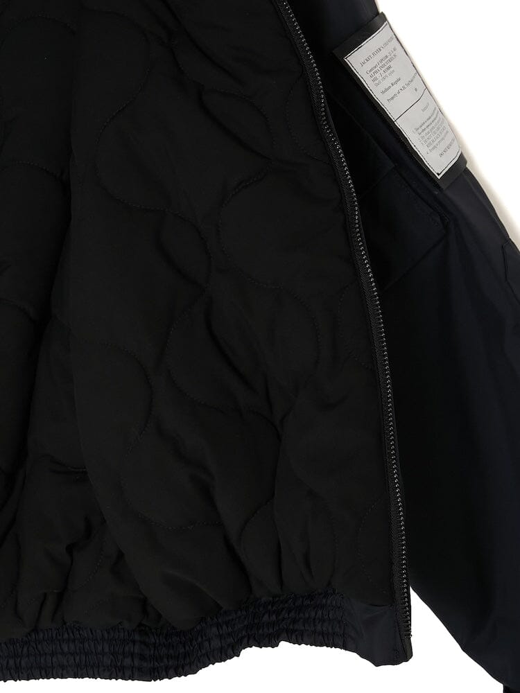 The Alpha X N. Hoolywood CWU-45P w/ Detachable Hood by Alpha Industries is a black quilted military blouson with an open zipper that reveals its detailed interior stitching and care label.