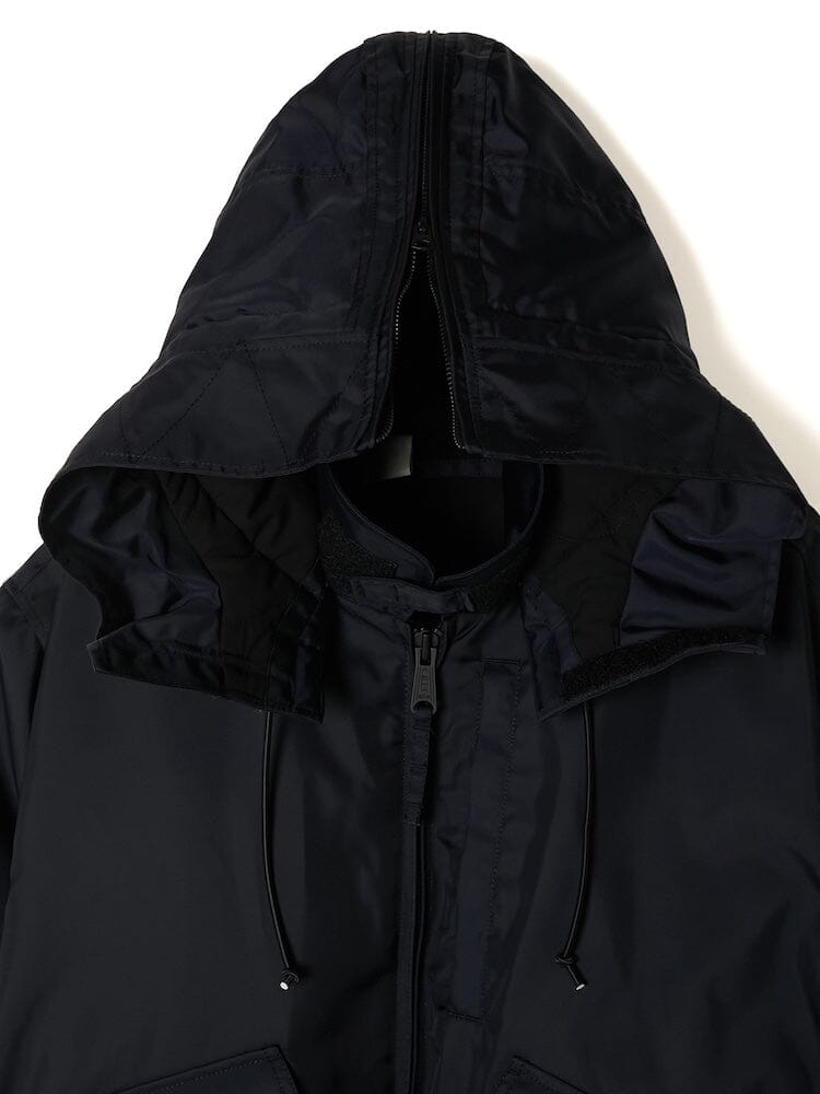 Zoomed-in image of the Alpha X N. Hoolywood CWU-45P jacket in black, featuring a partially open zipper that reveals the interior lining and drawstring accents. This polished design mirrors the timeless military blouson style characteristic of Alpha Industries, complete with a detachable hood.