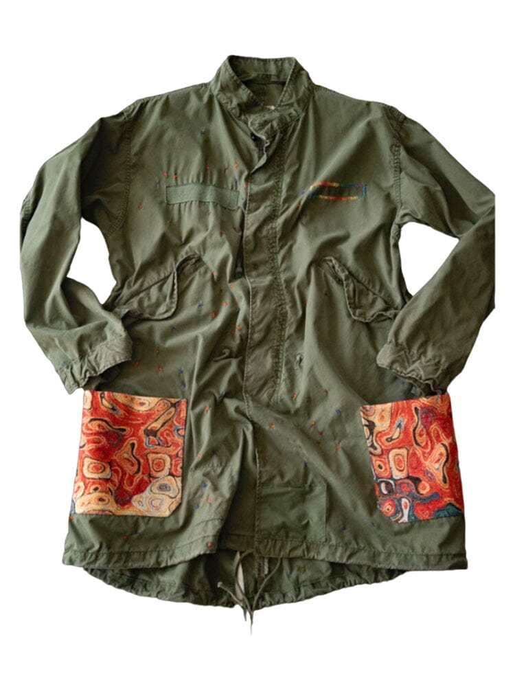 Alpha X Transnomadica Fishtail Parka by Alpha Industries, sage color with paint splatters, two large front pockets, red and orange abstract patterns.