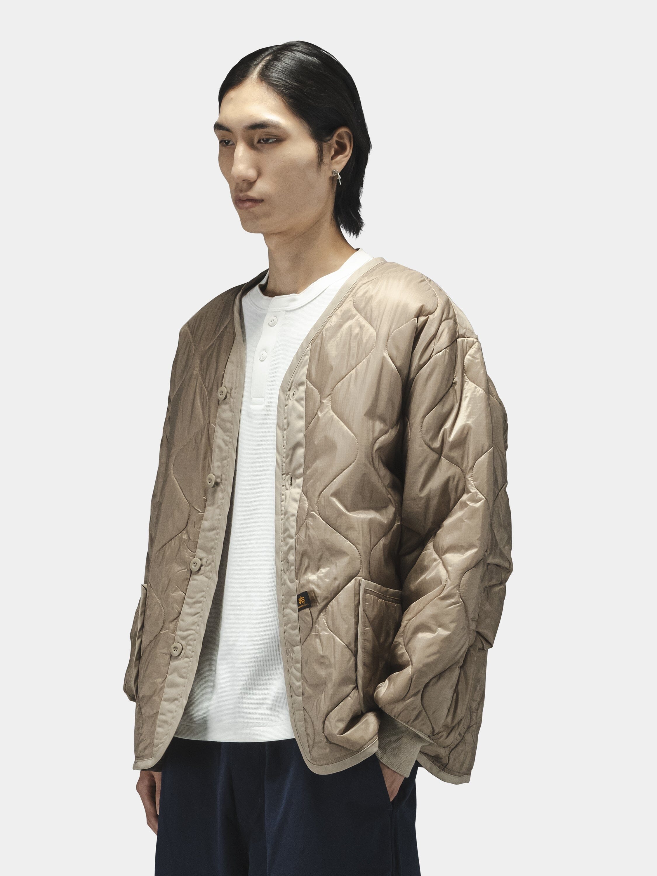 Alpha Industries Als/92 Liner in beige, worn over a white shirt and dark pants.