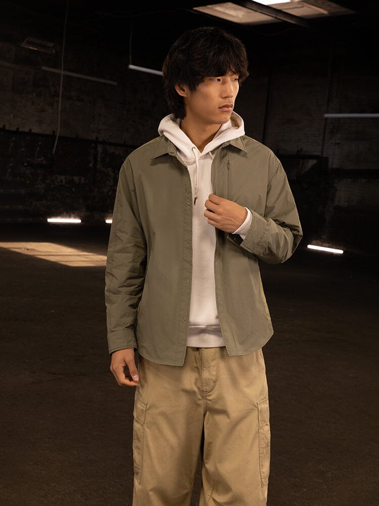 A person wearing the Astral Shirt Jacket in OG-107 Green by Alpha Industries.