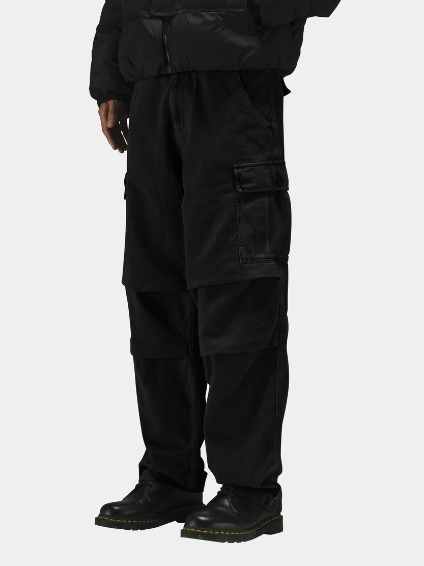 Alpha Industries Bdu Cargo Pant in black with button closures, paired with a black puffer jacket and black boots.
