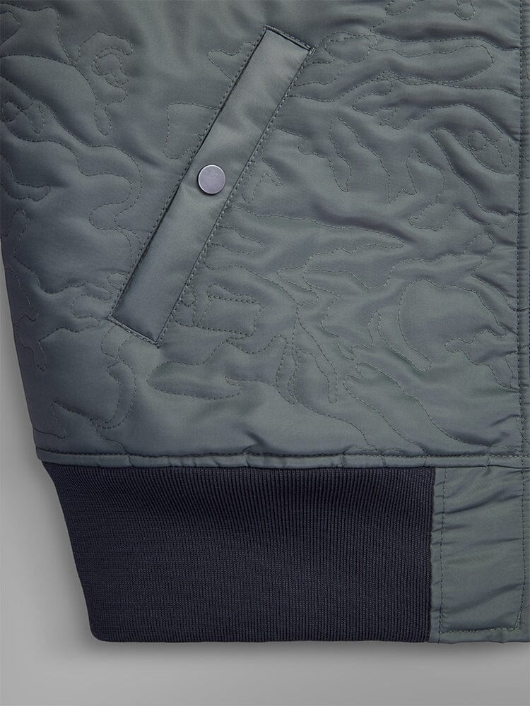 Close-up of the Camo Quilted MA-1 Bomber Jacket by Alpha Industries, showcasing a field gray design with a snap-button pocket and ribbed cuffs, crafted from water-resistant material.