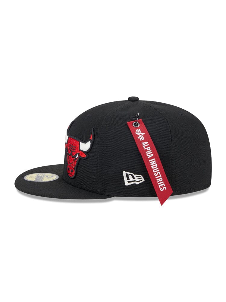 The Chicago Bulls X Alpha X New Era 59Fifty Fitted Cap, by Alpha Industries / NE-NBA, boasts a striking red bull embroidered team logo on the front, a sleek white logo on the side, and a vivid red Alpha Industries® tag attached.