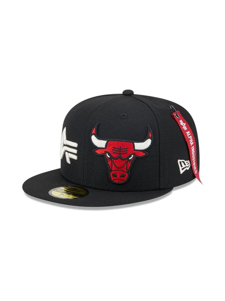 The Chicago Bulls x Alpha x New Era 59Fifty Fitted Cap is a black cap showcasing an embroidered team logo of a red bull and sleek white letters. It features a signature red tag on the side, perfectly aligning with the team's colors. This stylish piece is presented in collaboration with Alpha Industries® and NE-NBA.