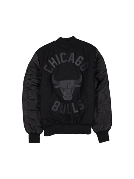 The Chicago Bulls x Alpha x New Era Wool Varsity MA-1 Bomber Jacket by Alpha Industries is a black bomber jacket adorned with a Chicago Bulls logo and lettering on the back, ideal for dedicated NBA fans.