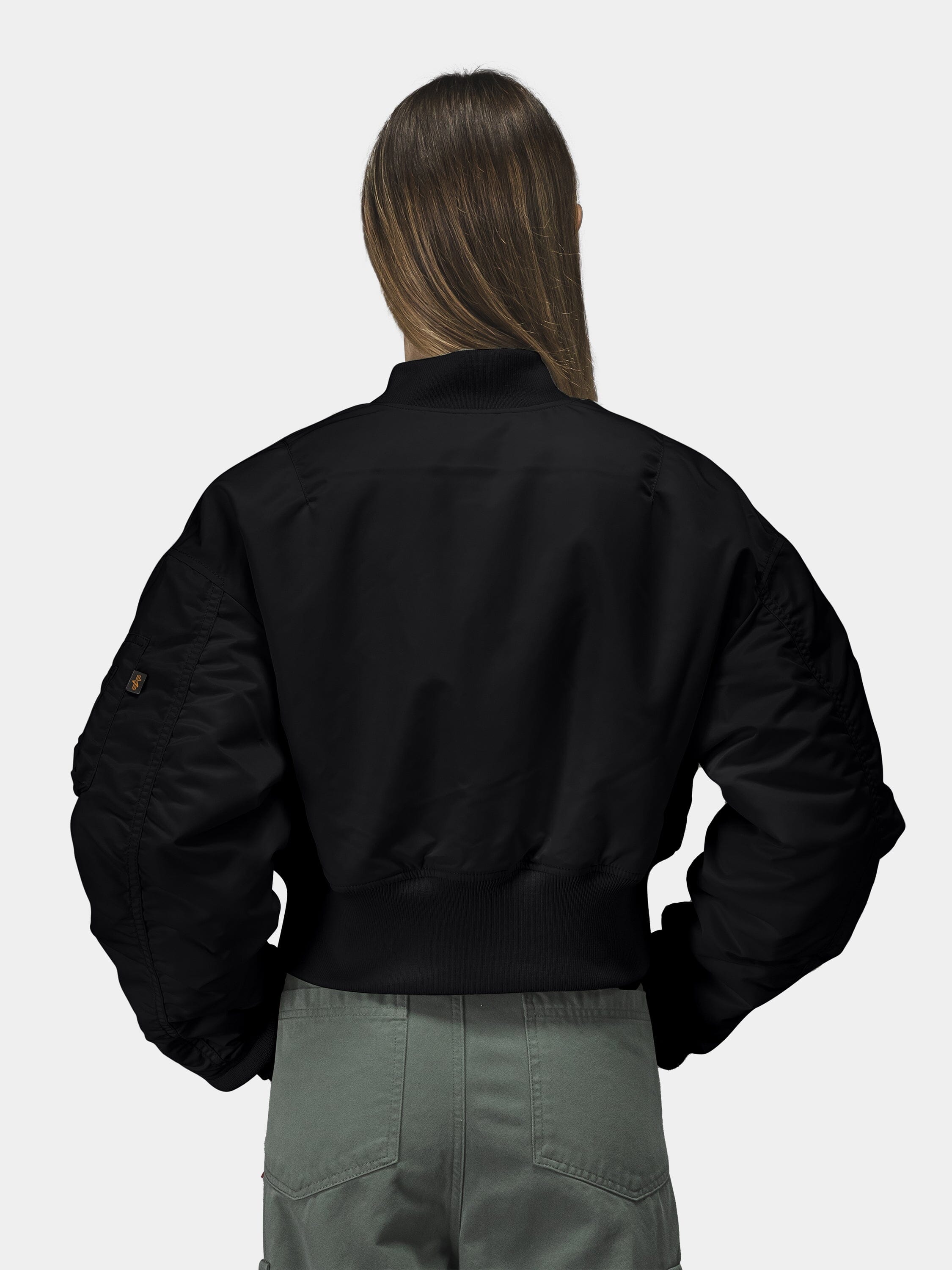 Alpha Industries Cropped MA-1 Flight Jacket Womens in black, paired with olive green pants.