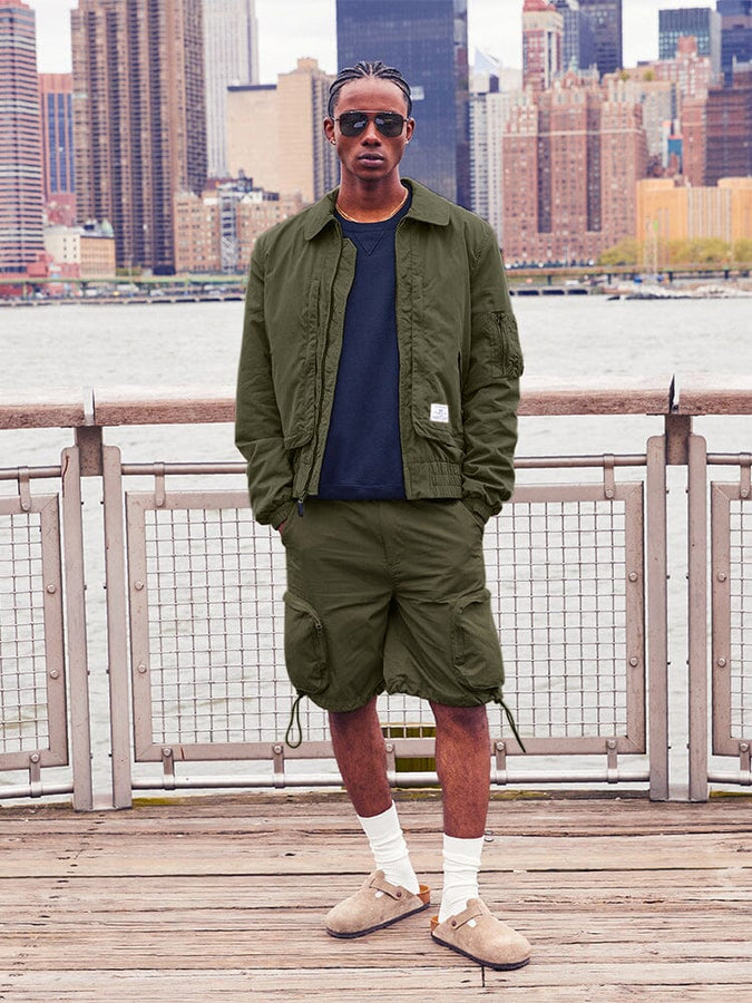 Alpha Industries Cwu 36/P Pull On Short, dark green jacket, black shirt, white socks, brown slip-on shoes.
