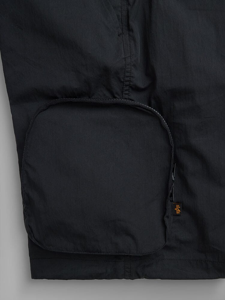 Alpha Industries Cwu 36/P Pull On Short, black, large rounded zippered cargo pocket, small orange and black tag near zipper.