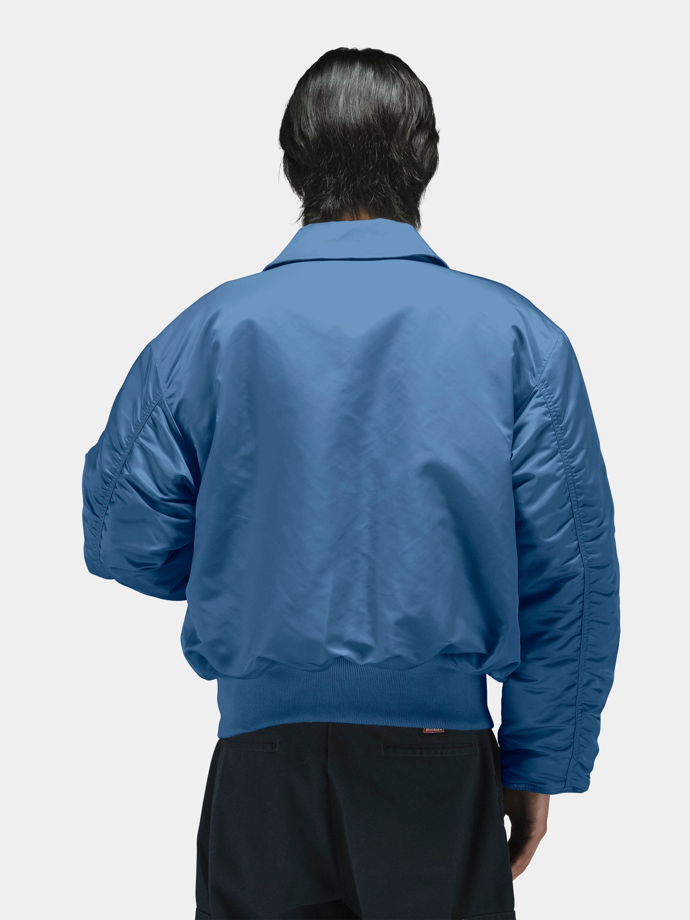 Alpha Industries Cwu 45/P Bomber Jacket in blue with black pants, featuring ribbed cuffs and waistband, front zipper closure.