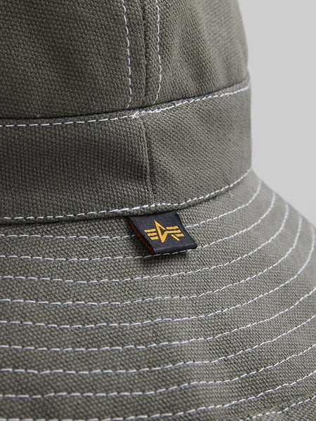 Alpha Industries Canvas Daisy Mae MA-1 Bucket Hat, green canvas with white stitching, geometric black and yellow tag.