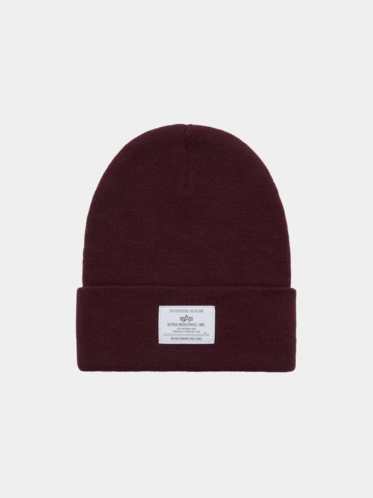 Essential Beanie by Alpha Industries in Cedar Red with folded cuff and rectangular Alpha paper label on the front.
