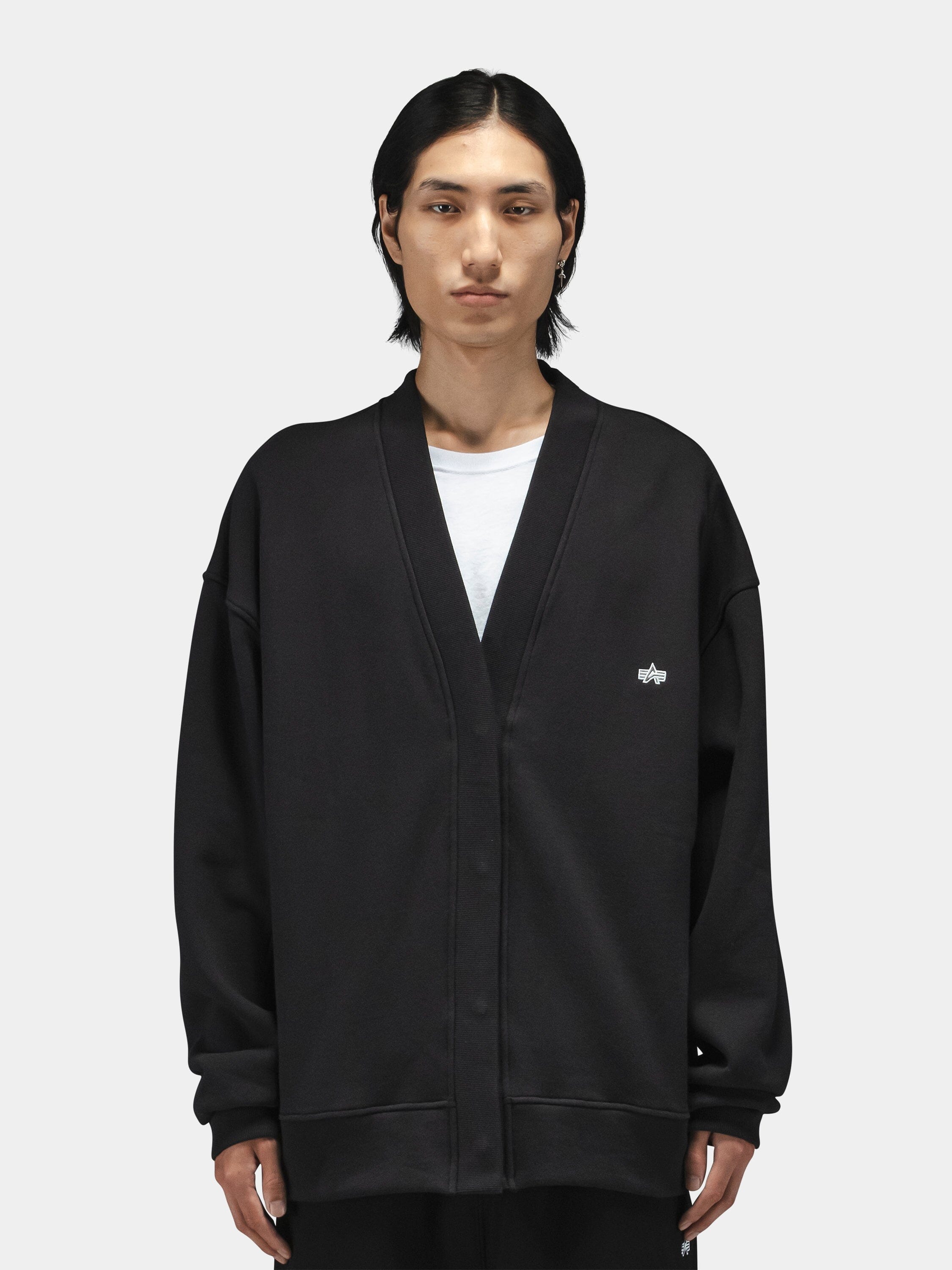 Alpha Industries Essential Cardigan in black with hidden snap closure, worn over a white t-shirt.