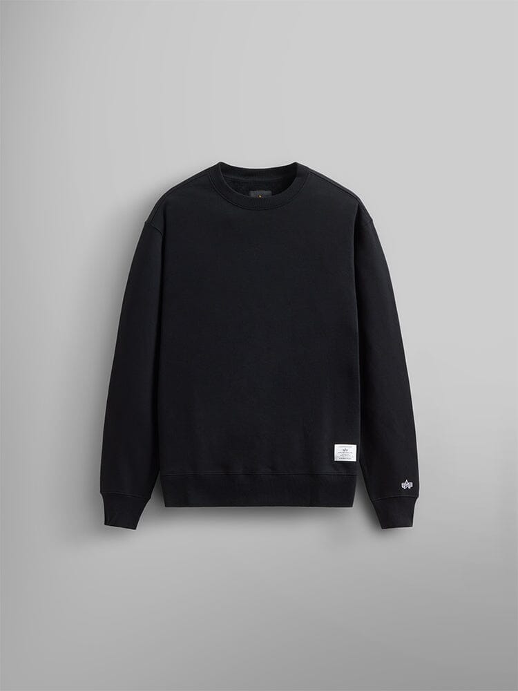 The Alpha Industries Essential Crewneck is a black unisex sweatshirt and is crafted from a comfortable cotton blend and features a small white label at the bottom left.