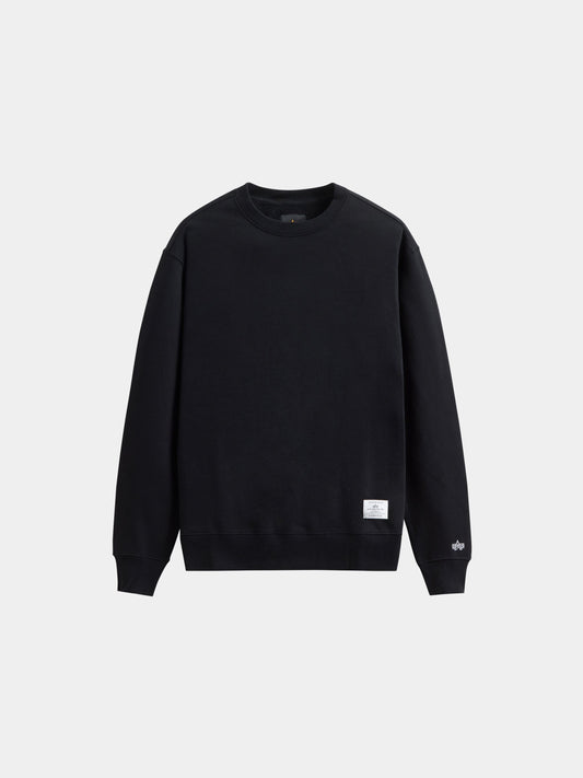 Alpha Industries Essential Crewneck, black sweater with long sleeves, ribbed cuffs and hem, and a small white tag near the waistband.