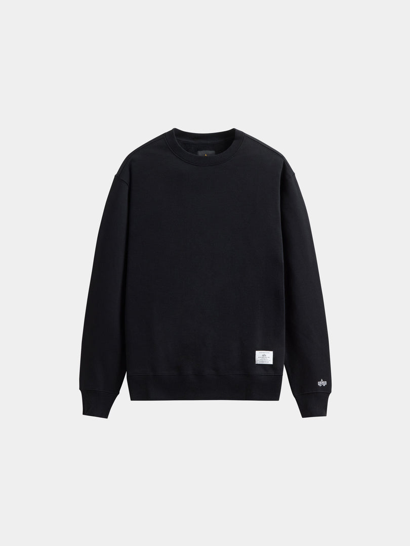 Alpha Industries Essential Crewneck, black sweater with long sleeves, ribbed cuffs and hem, and a small white tag near the waistband.