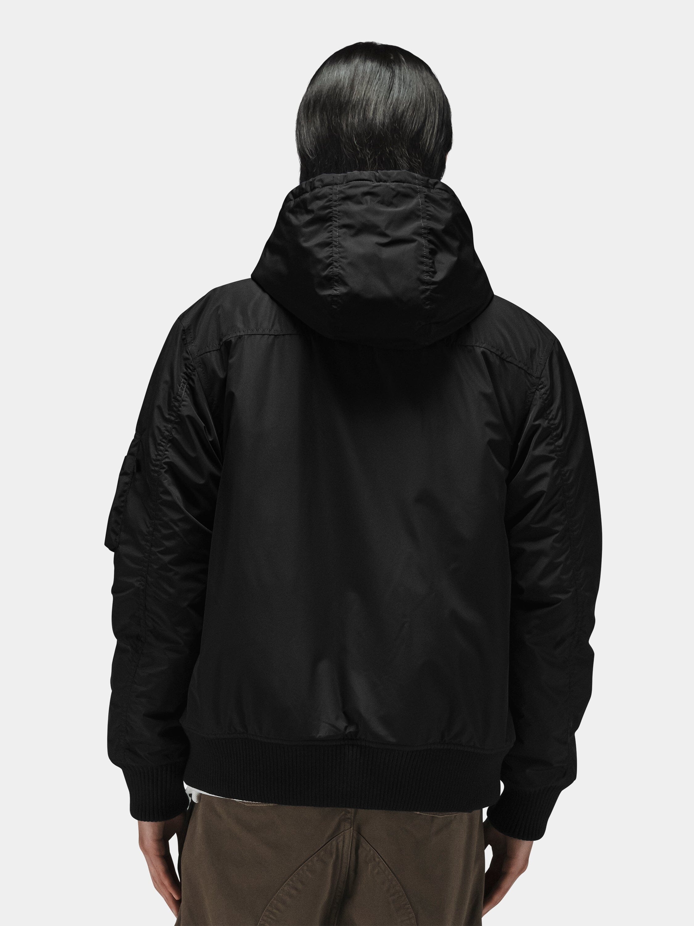Alpha Industries Hooded Rib Flight Jacket in black with utility sleeve pocket, brown pants.