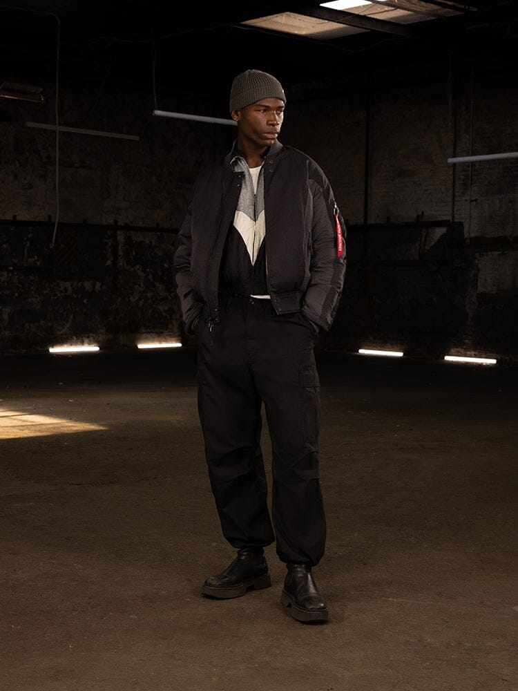 A person is wearing an Alpha Industries Insulated MA-1 Bomber Jacket, complemented by a beanie and boots.