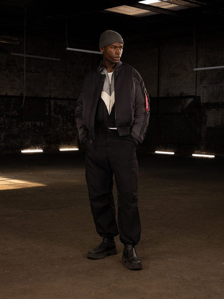 A person is wearing an Alpha Industries Insulated MA-1 Bomber Jacket, complemented by a beanie and boots.