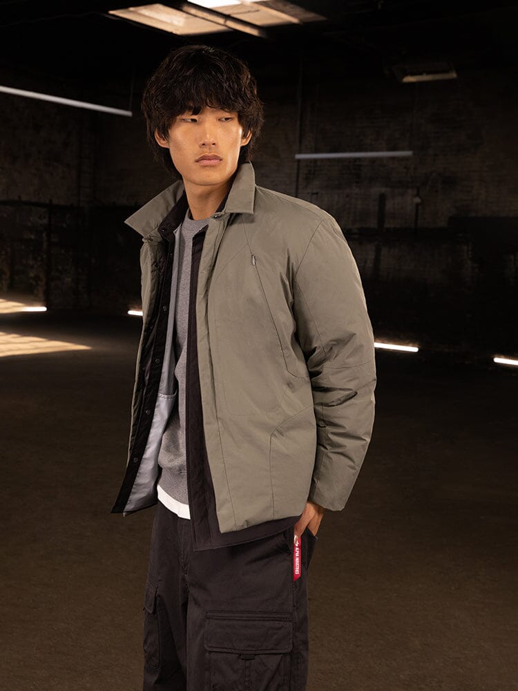 A person with medium-length hair is wearing the Insulated Shirt Jacket by Alpha Industries, exuding a casual streetwear look.